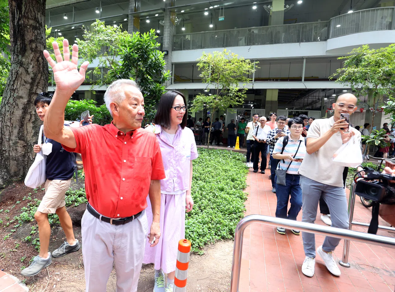 黄国松（左一，穿红衣）趁午餐时间，到商业区的厦门街熟食中心。他在那里逗留了约45分钟，食客多是在附近工作的上班族。（邝启聪摄）