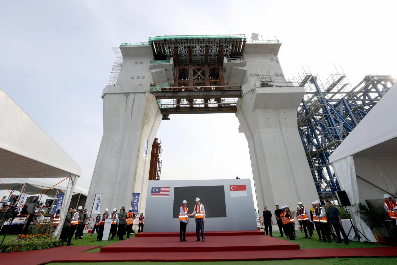 新柔地铁跨海高架轨道的47号桥墩（左侧）由马来西亚承建，右侧的48号由新加坡负责。图为李显龙总理（中央右）和马国首相安华（中央左）在高出海平面26米的两座桥墩之间握手，庆祝连接段的落成。（何家俊摄）