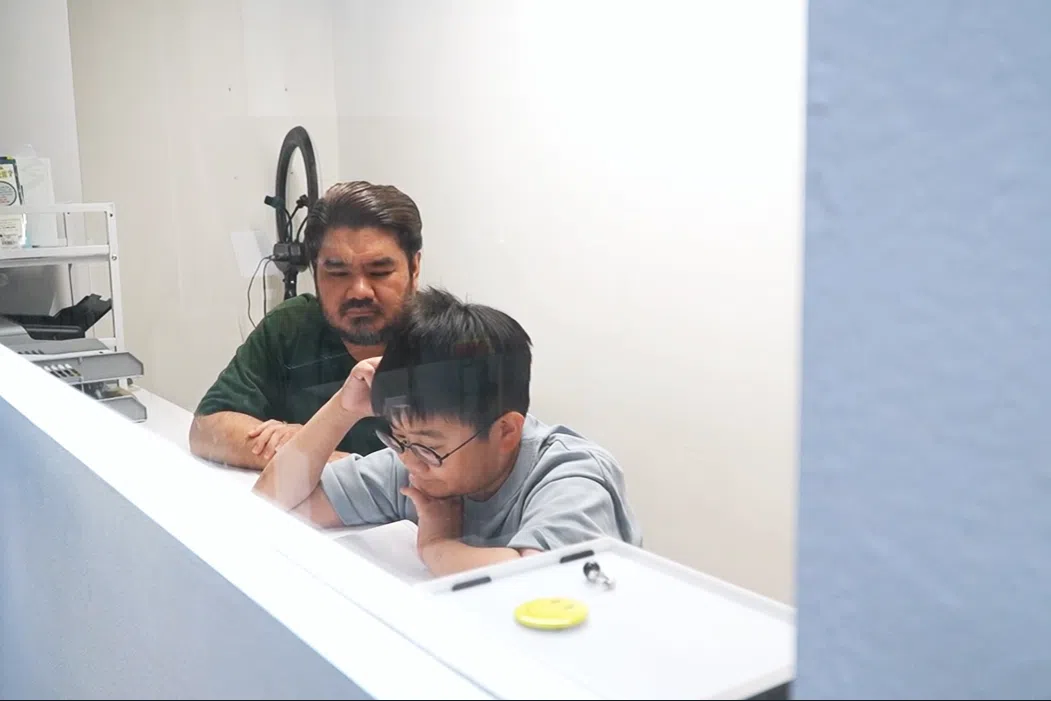 李至成和儿子李柏曦每天都在家中的玻璃书房（戏称“鱼缸”）复习课业。（视频截图）