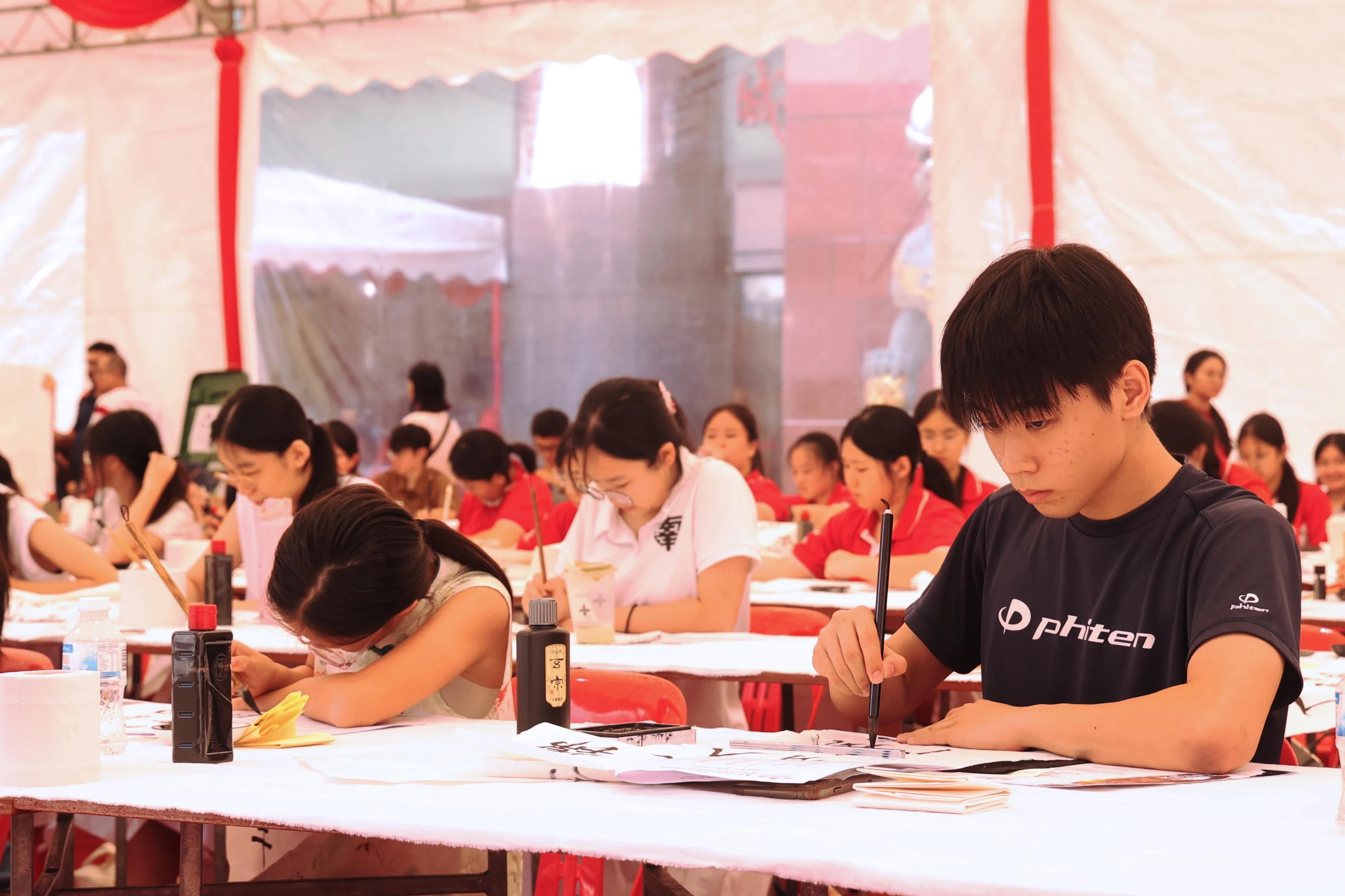 参赛的日本学生杉田幸谦（黑衣者）正聚精会神地写书法。（邬福梁摄）
