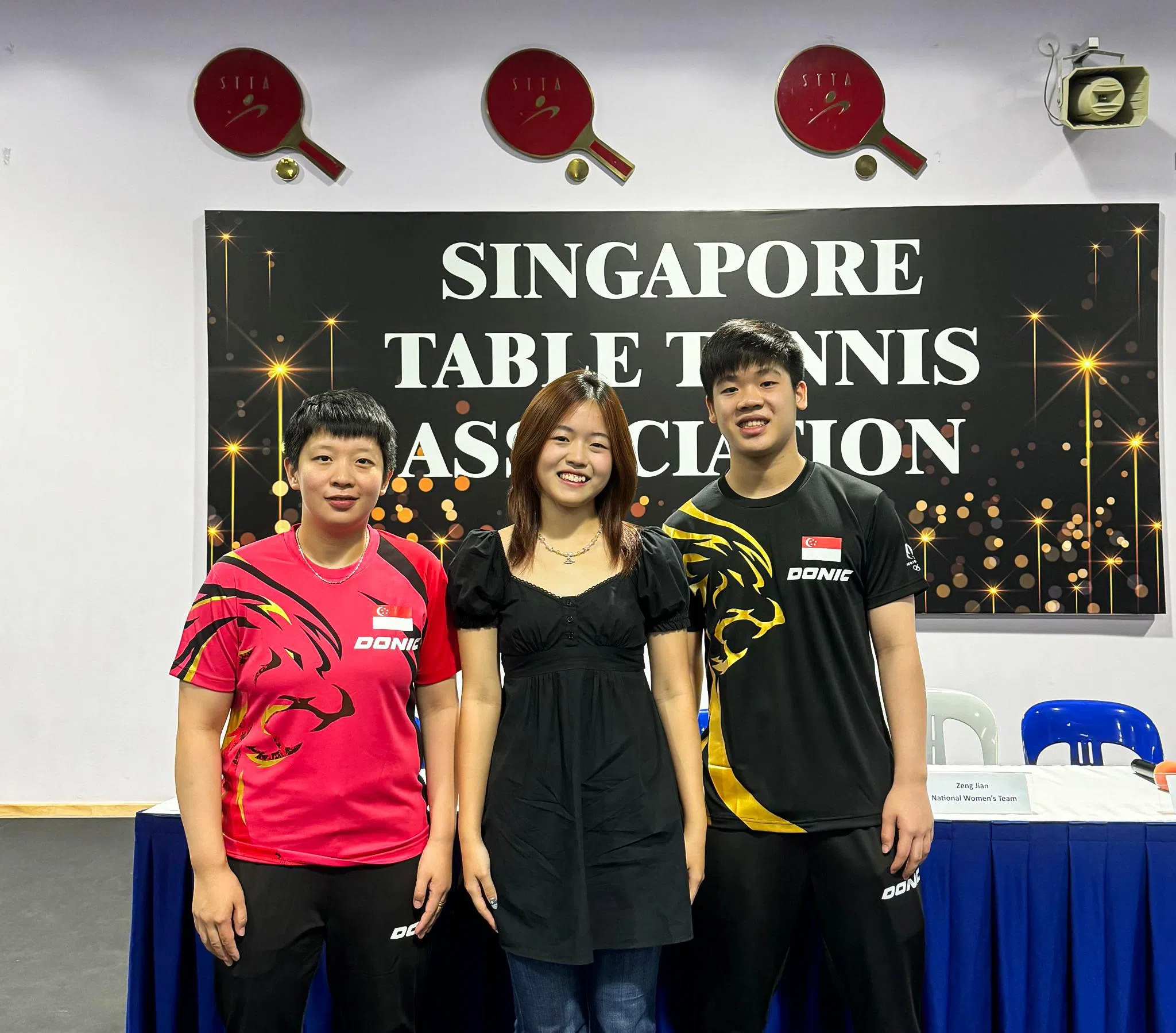 华侨中学学生许瑞恩（中）所设计的球衣获得乒总青睐，我国选手将穿上这两款红色和黑色的球衣征战巴黎奥运。（新加坡乒乓总会提供）