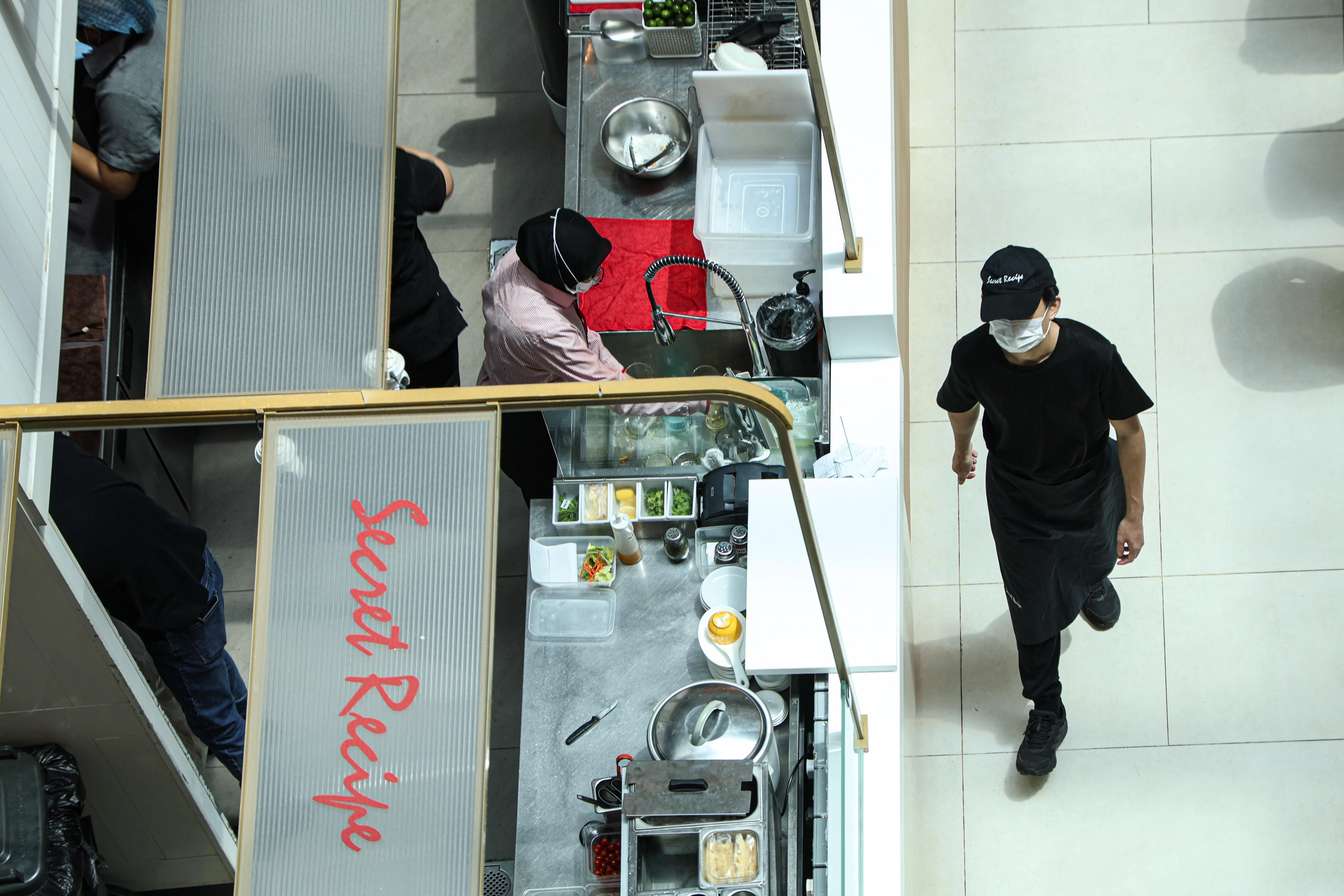 狮城大厦商场有冷气，所以绝大多数餐馆和小吃店的餐饮员工仍然戴着口罩。（关俊威摄）