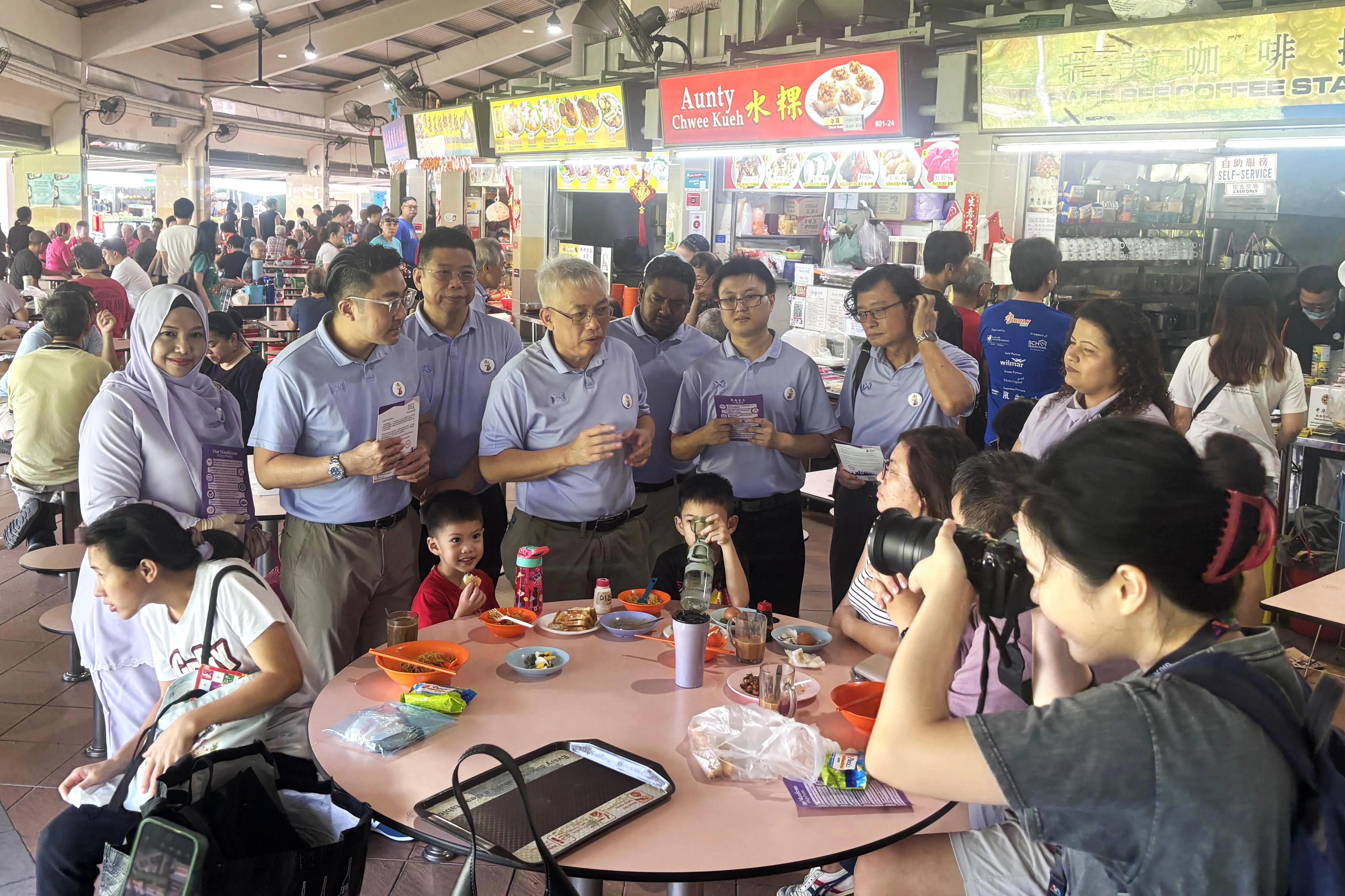 吴明盛（左四）星期六（4月12日）早上与团队走访淡滨尼11街第137座的圆巴刹与小贩中心，并向媒体介绍四名新人。（王辉雯摄）