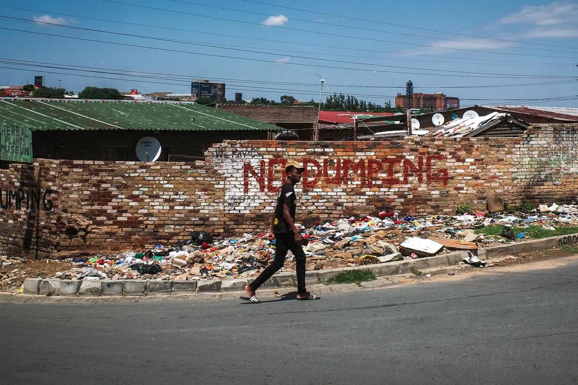 在“禁止倾倒垃圾”的红字前，行人匆匆走过。（叶振忠摄）