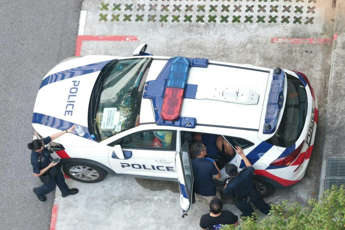 嫌凶事发后被押到停在楼下的一辆警车里。（梁麒麟摄）