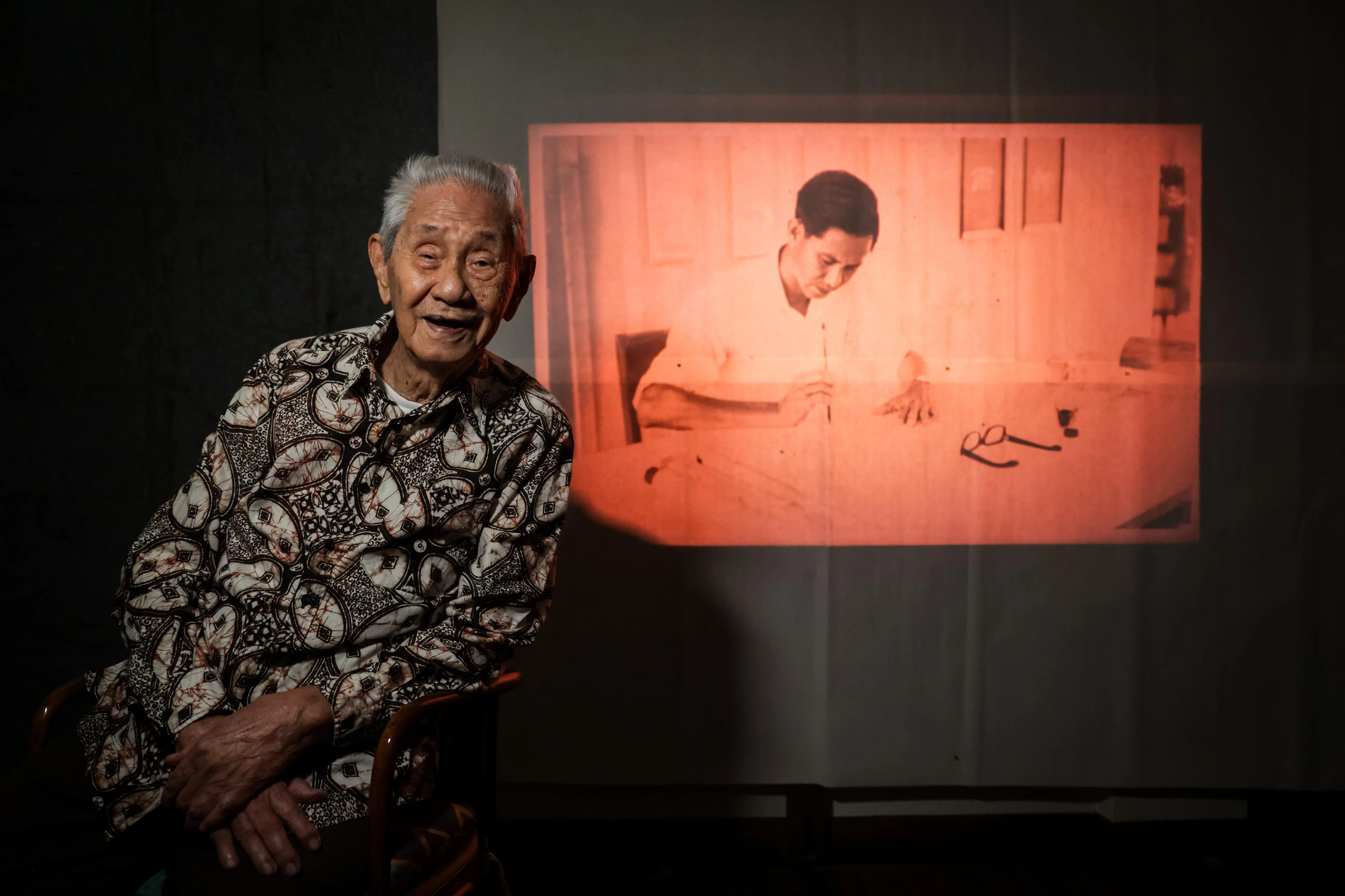 103岁的林子平与年轻写书法的他相映成趣。（叶振忠摄）