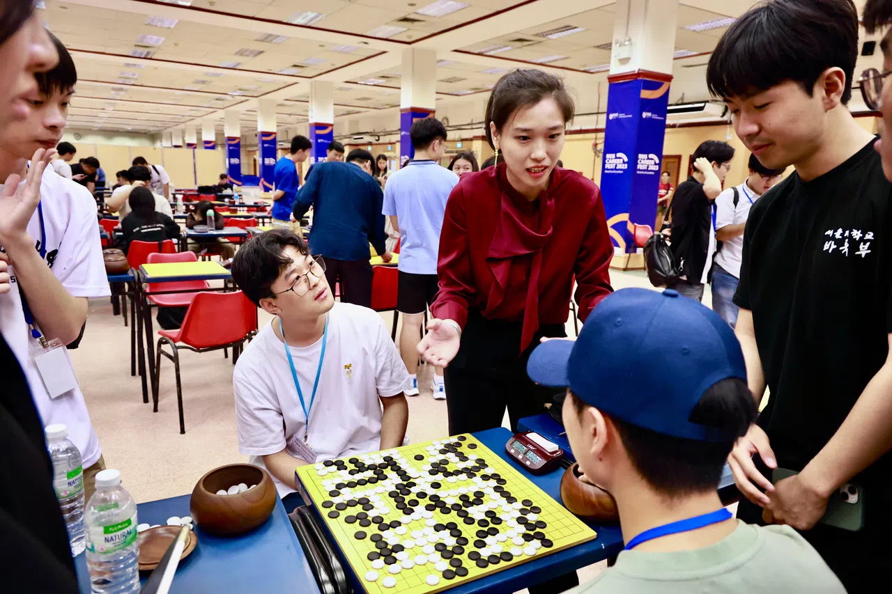 新加坡围棋协会秘书裴今令（身穿红衣者）担任比赛的总裁判。图为裴今令在比赛现场为选手化解得分争议。（特约摄影陈来福）