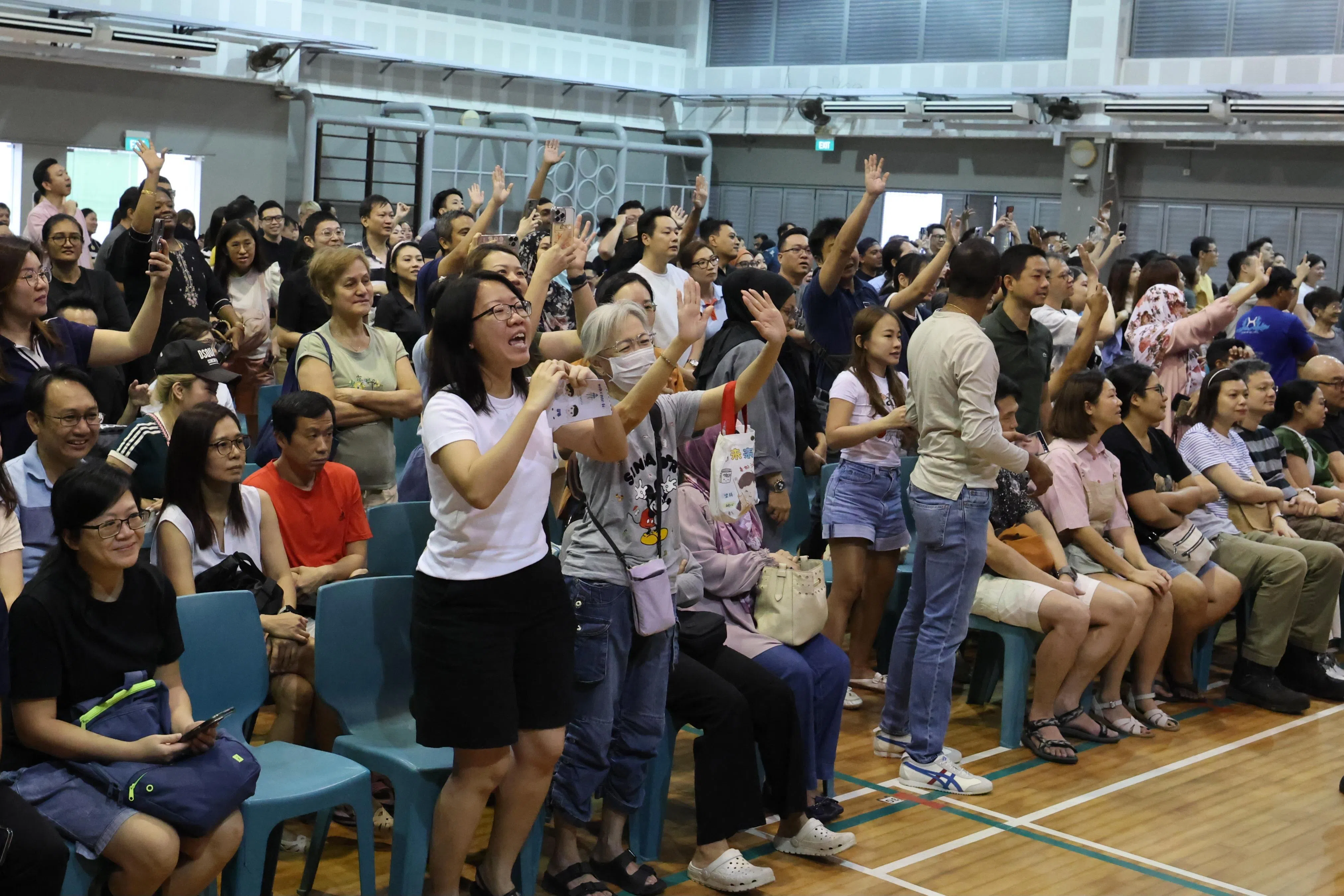 家长陪同上小学的孩子到维林小学报到后到礼堂集合，看着孩子列队准备到食堂，第一次自己买食物，纷纷站起来向孩子挥手打气，以示鼓励。（梁麒麟摄）