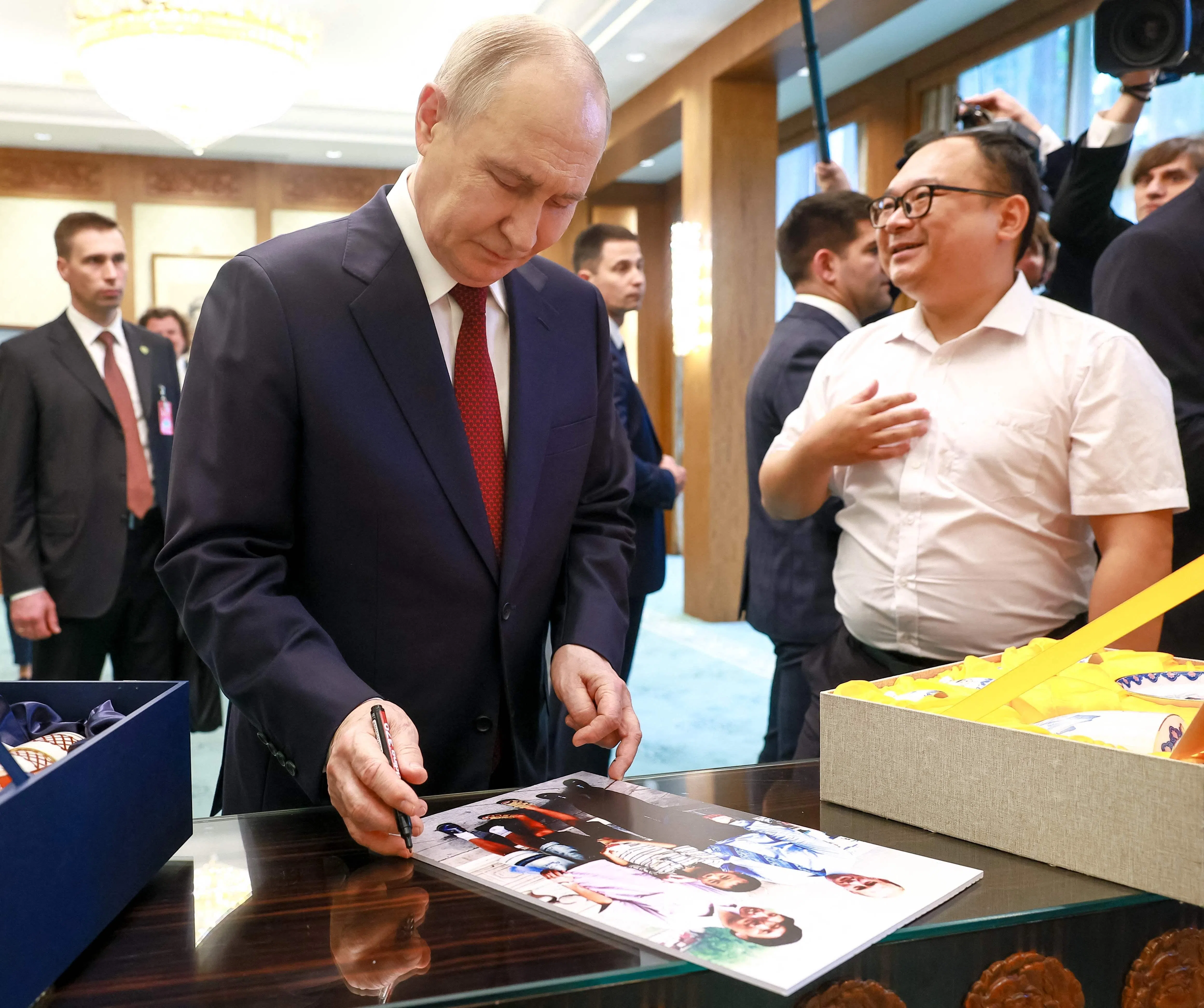 俄罗斯总统普京星期三（5月20日）在人民大会堂与26年前访华时在公园偶遇的中国男孩彭湃重逢，互赠礼物。（法新社）