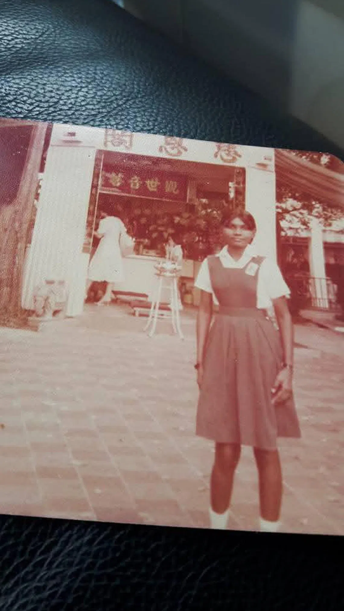 莎拉瓦蒂当年穿着小学校服，在华人寺庙前拍照。（受访者提供）