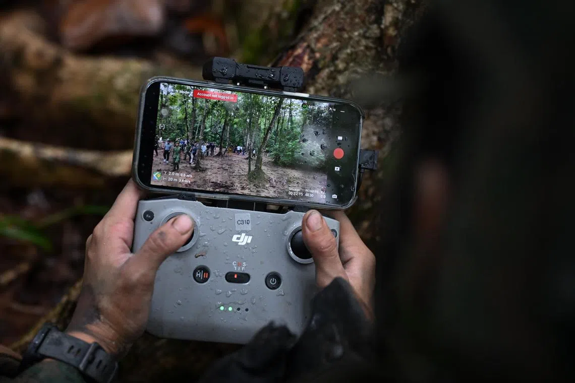 一名新兵在德光岛的基本军训中心进行野外训练时，在教官指导下尝试操控无人机。（海峡时报）