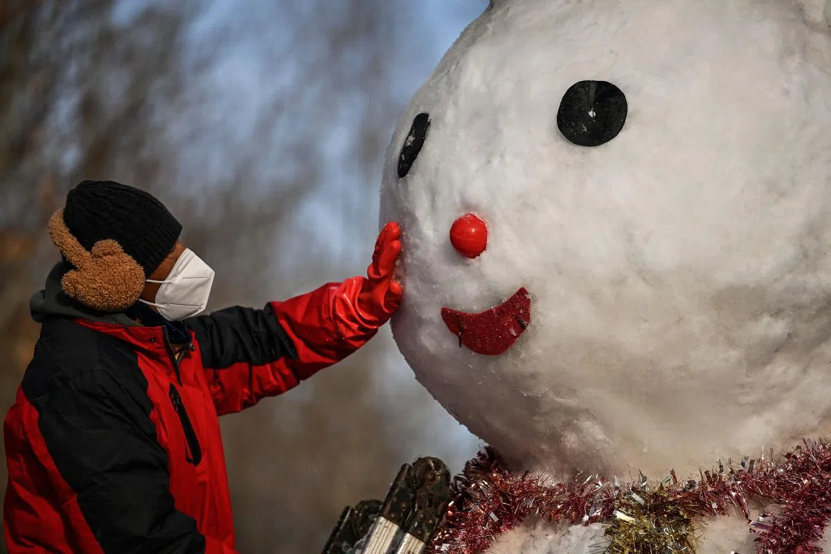 工作人员星期一（1月23日）在北京一座公园堆雪人。（法新社）