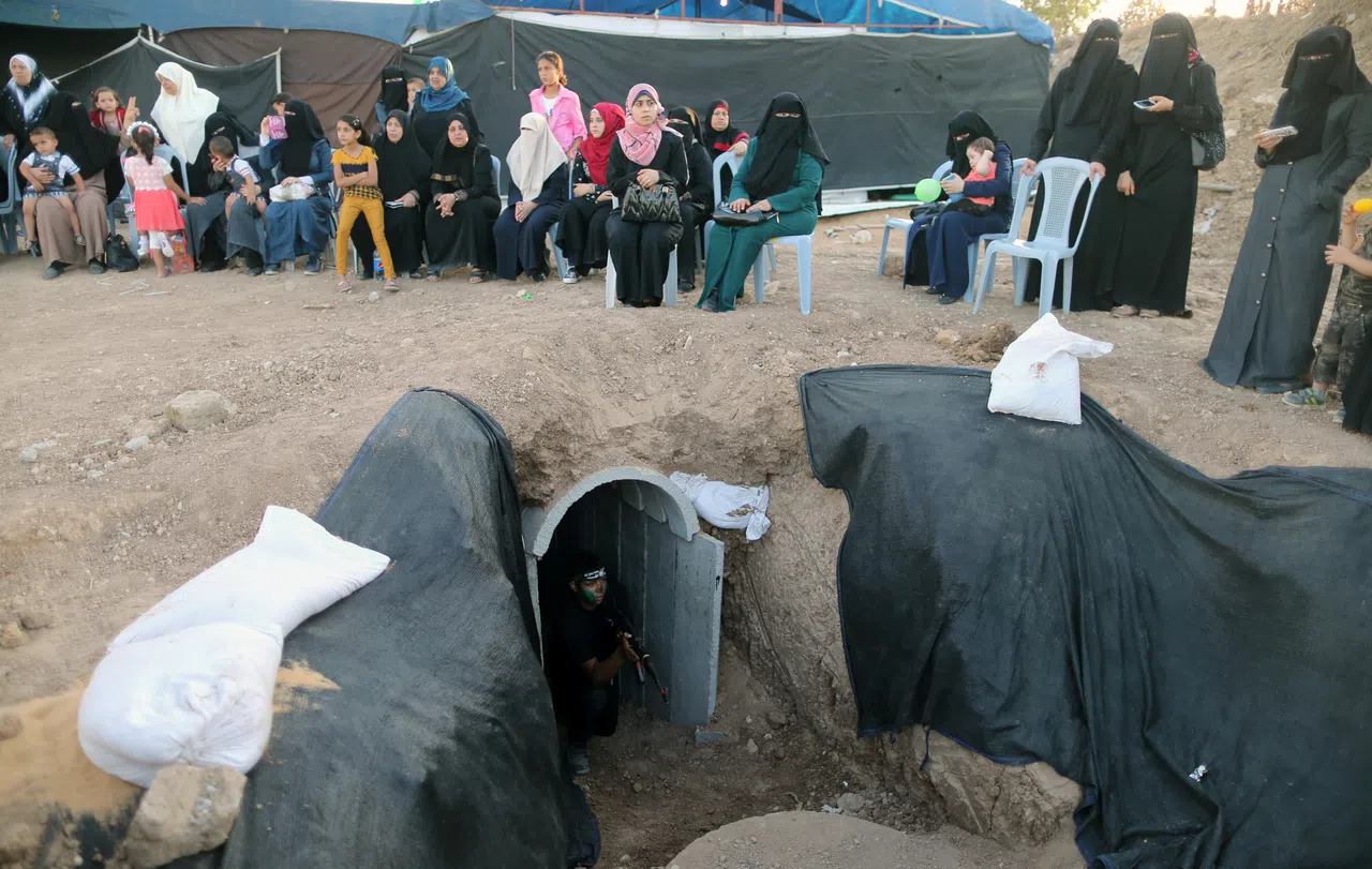 巴勒斯坦人对加沙地底隧道早习以为常，地面上妇女小孩生活如常，地底下青少年青少年进行着隧道突袭演练。（路透社）