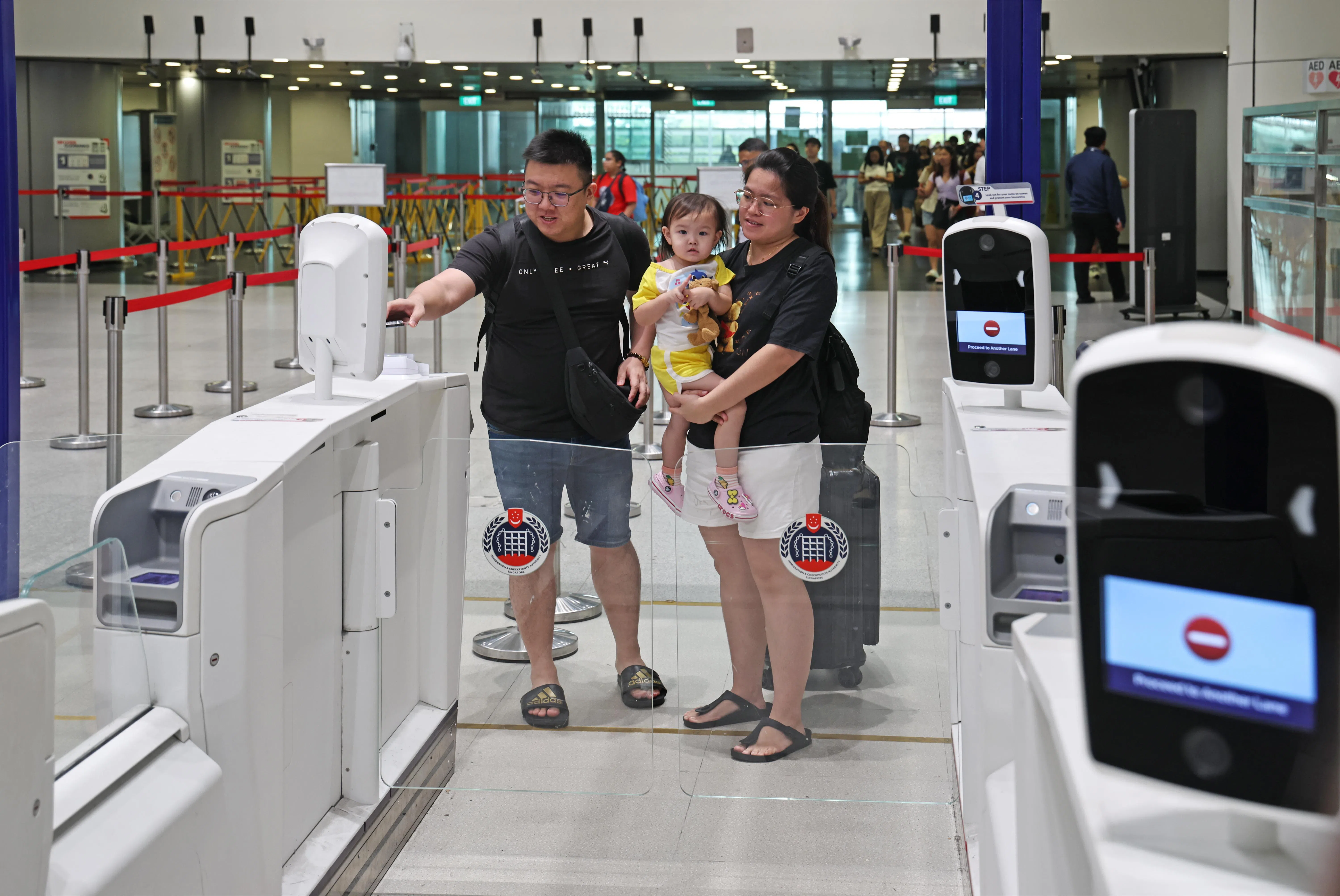 吴伟良（33岁）出示QR码进行扫描，很快便与颜慧玲（31岁）和女儿一起完成通关程序。（陈渊庄摄）