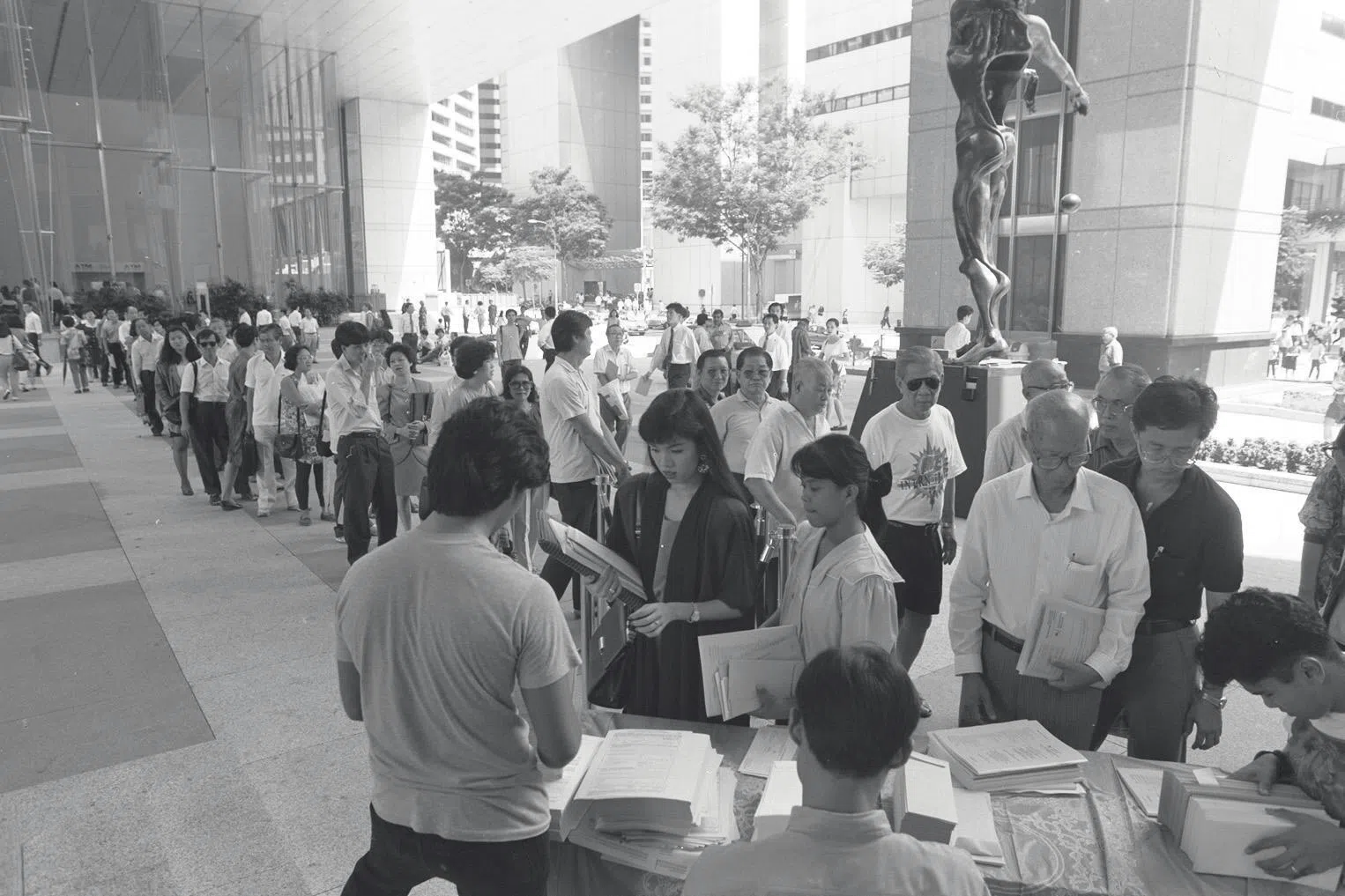 1993年，新加坡政府推出全民拥股计划，让新加坡所有成年公民拥有新加坡电信公司（简称新电信）的股票。图为大批民众当年在银行外排队申请认购新电信股票。（档案照片）