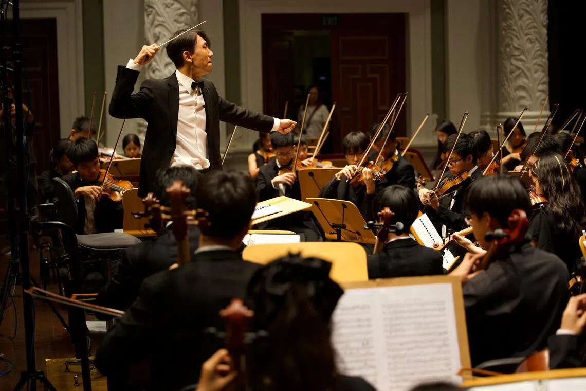2025年8月，新加坡青年爱乐交响乐团与来访的中国爱乐青少年交响乐团，组成联合乐团在维多利亚音乐厅演出，罗威（站立者）任音乐总监。（受访者提供）