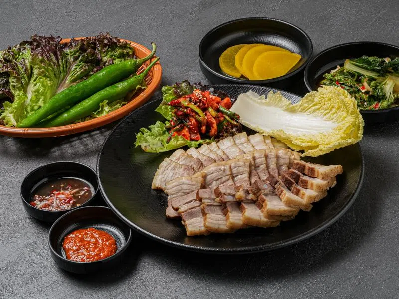 用当归、八角与桂皮慢煮的韩式菜包肉，切片后裹在生菜或白菜里享用。（餐馆提供）