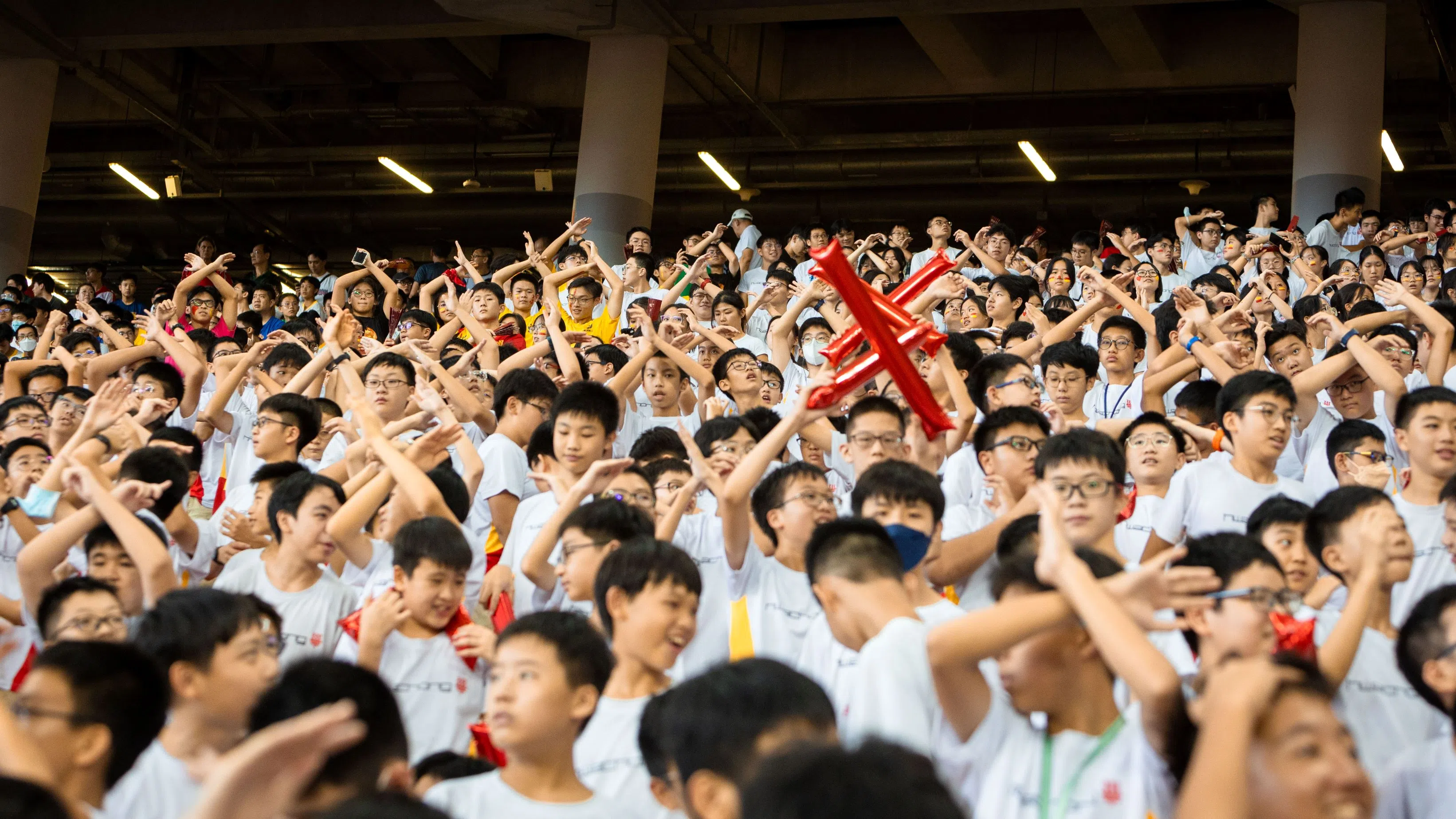 华中学子边呐喊口号，边挥动手势，为赛场上的校队助威。（华侨中学何奕勋摄）