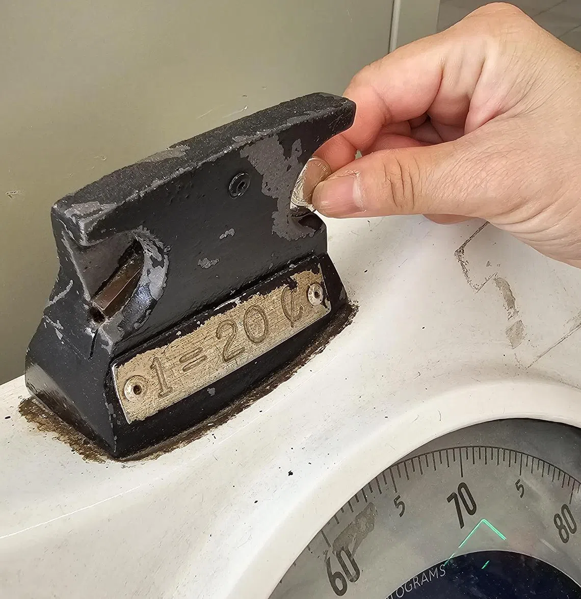 在这款金属机械秤投下两角钱，就可测量体重。这样的体重测量器在本地现在已非常少见。（梁麒麟摄）