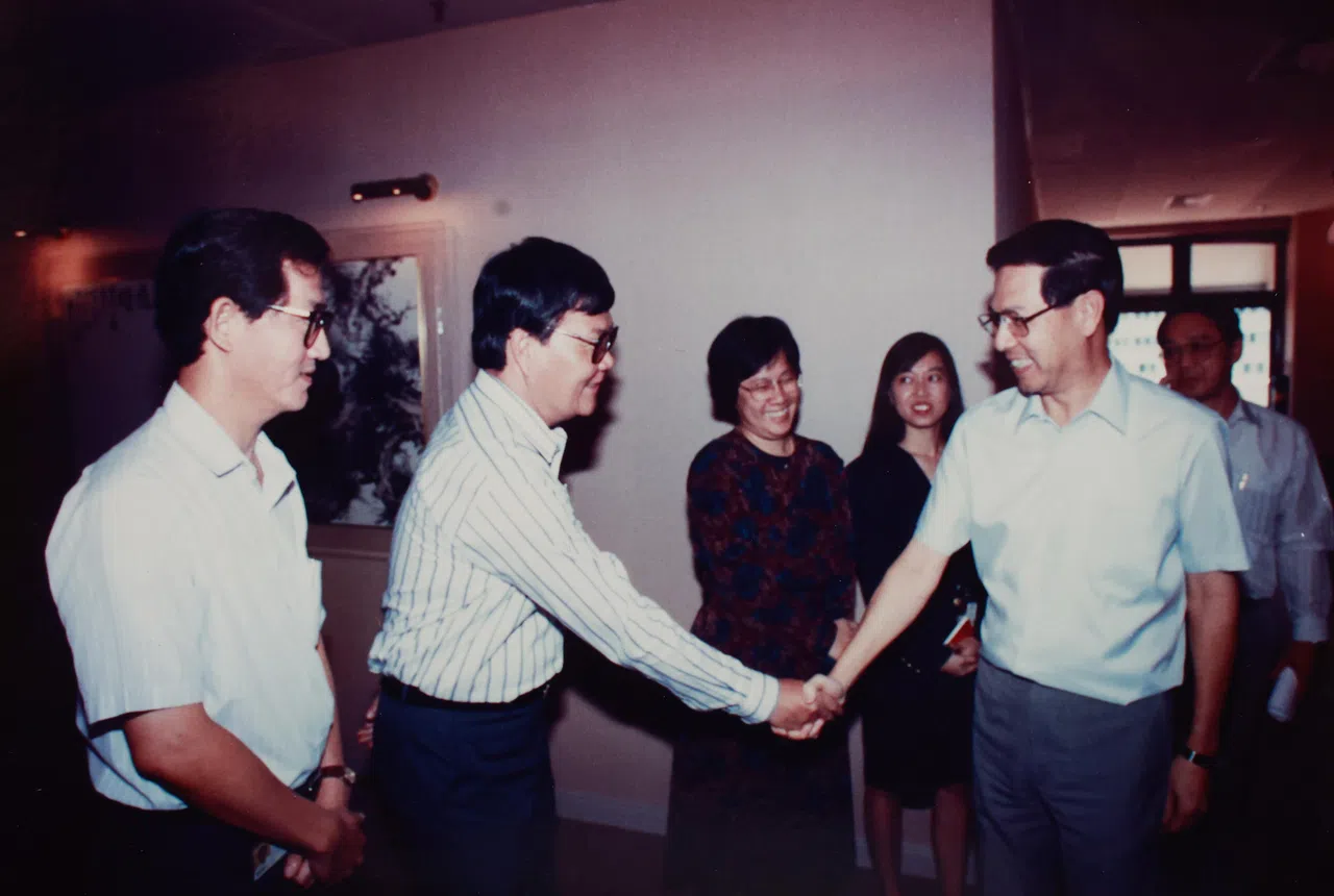 已故总统王鼎昌先生（右一）参观早报编辑组时和陈庆来握手，左一为时任编辑组副主任的郭坤福。摄于1990年代。（陈庆来提供）