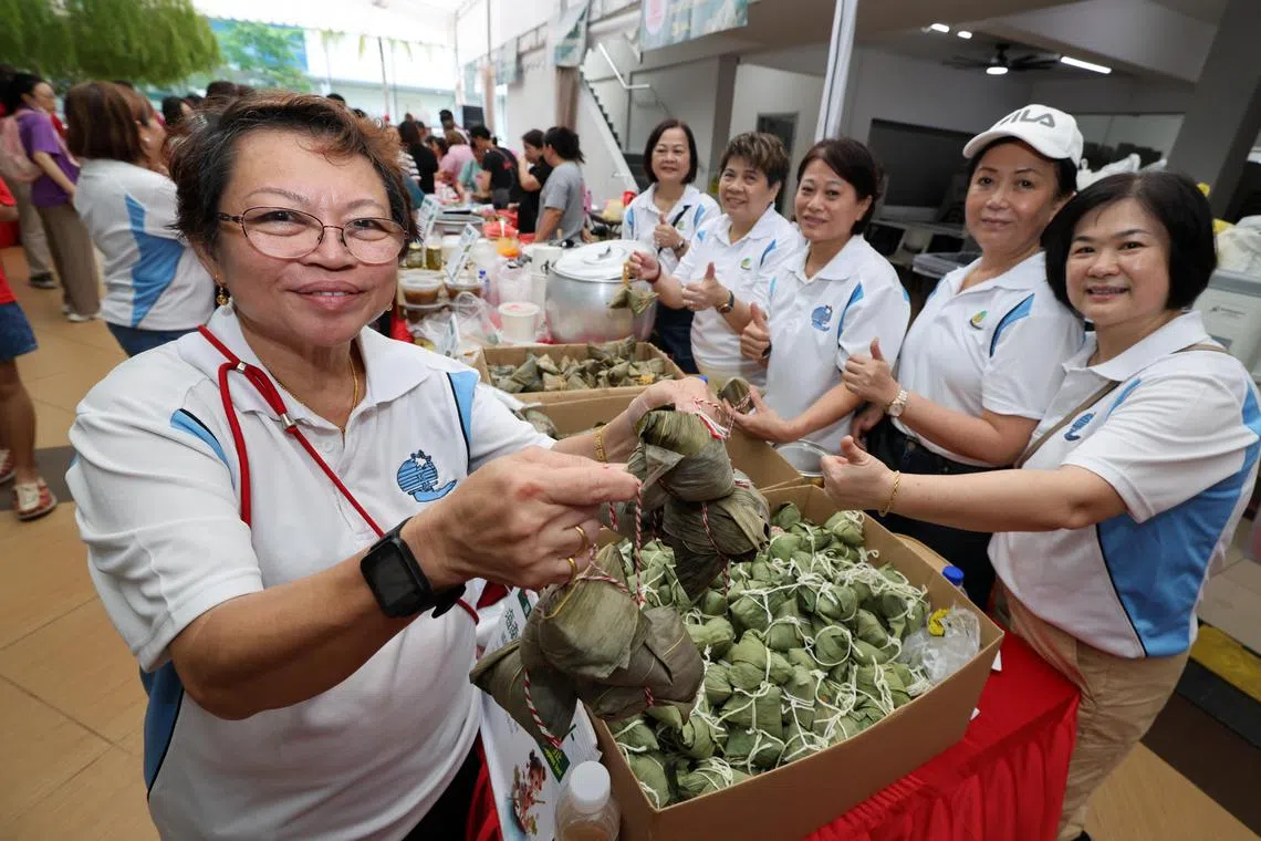 琼州天后宫董事欧宗谚（左一）和同伴们一起在“端午嘉年华”上售卖手包粽子。（梁麒麟摄）