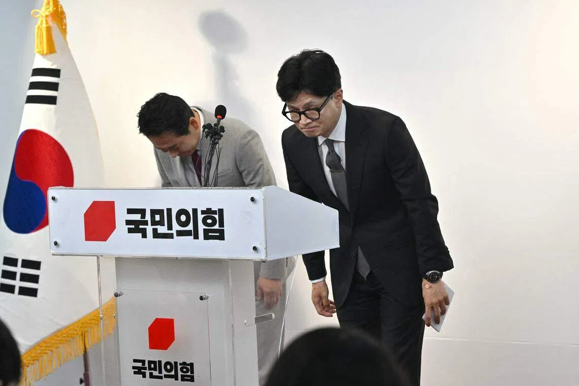 韩国国民力量党党首韩东勋（右）星期四在首尔党总部举行的新闻发布会上鞠躬，为他领导的执政党在国会选举中惨败引咎辞职。（法新社）