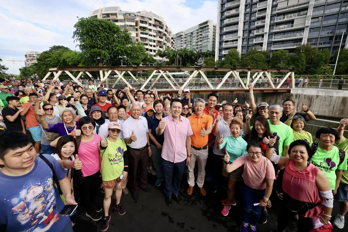 财政部兼人力部高级政务次长黄伟中（中，粉红上衣者）和约600名达曼裕廊居民出席活动，庆祝人行桥的启用。 （邝启聪摄）
