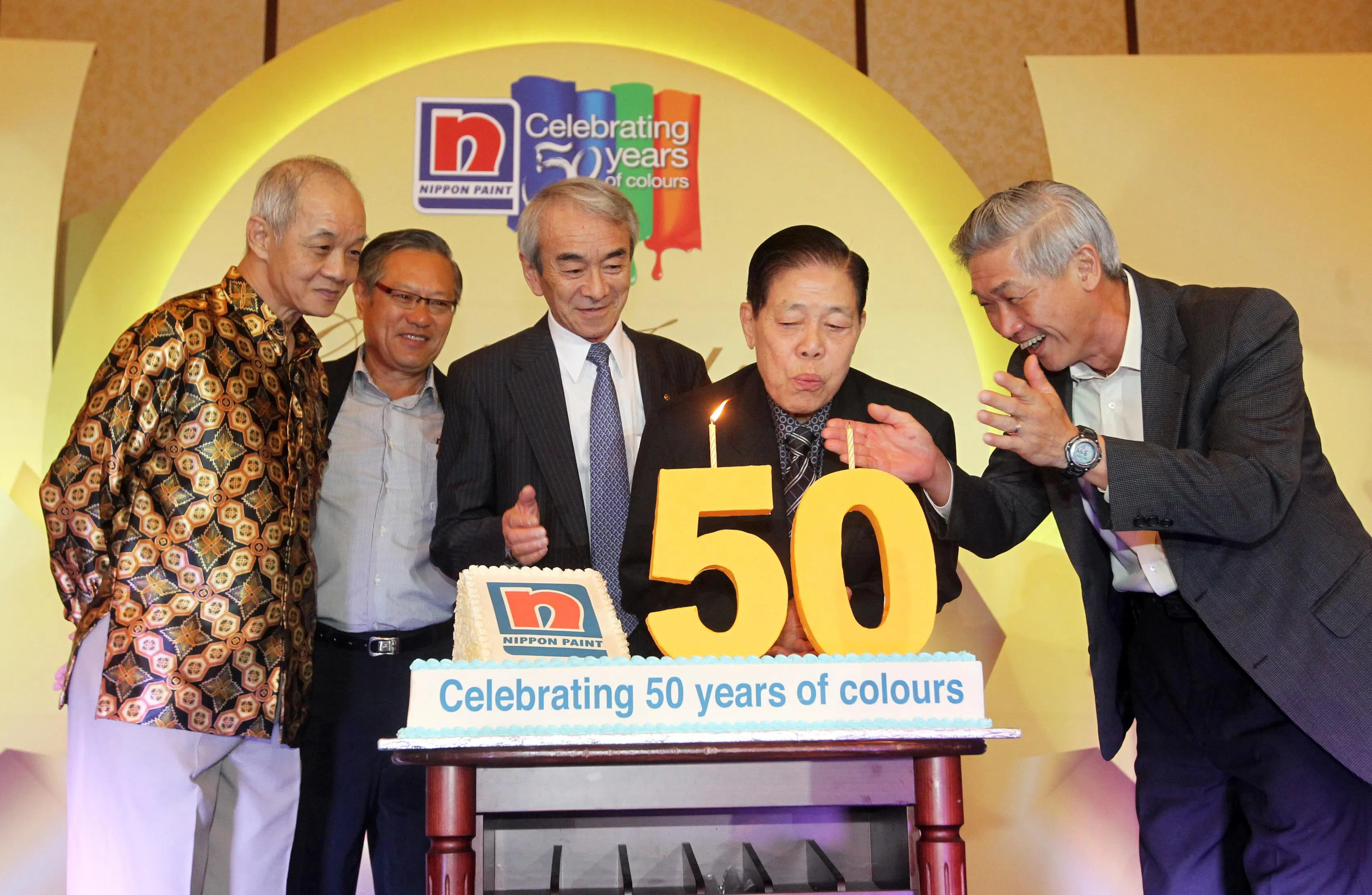 为配合50周年庆，日本漆制造商新加坡立时集团捐出600万元给慈善机构，帮助弱势儿童。图为立时集团创办人吴清亮吹蜡烛切蛋糕，庆祝集团成立的50周年。（档案照片）