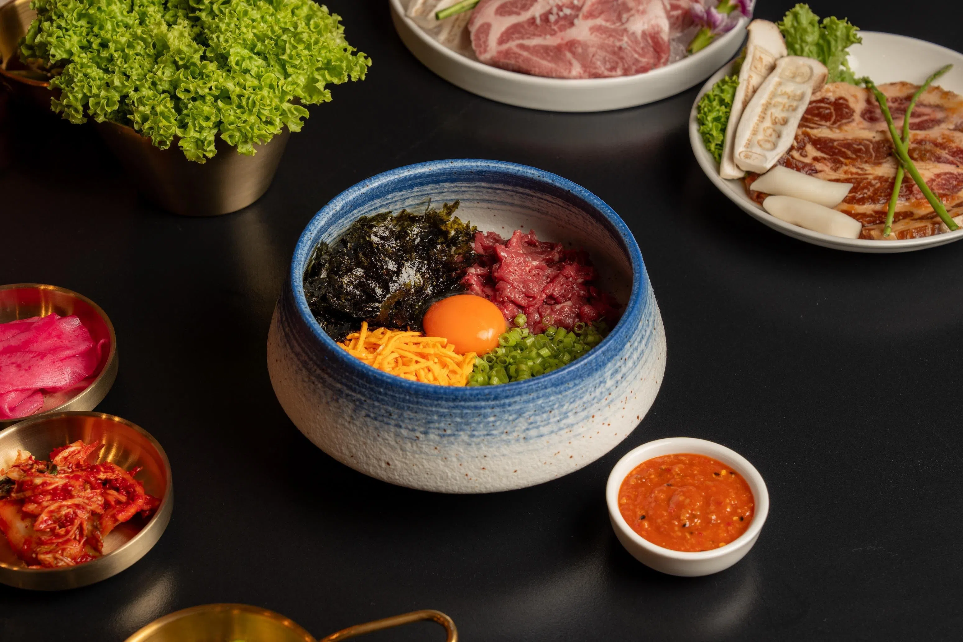 韩式生牛肉拌饭，将生牛肉、蔬菜、米饭与酱料拌匀享用，口感层次丰富。（餐馆提供）