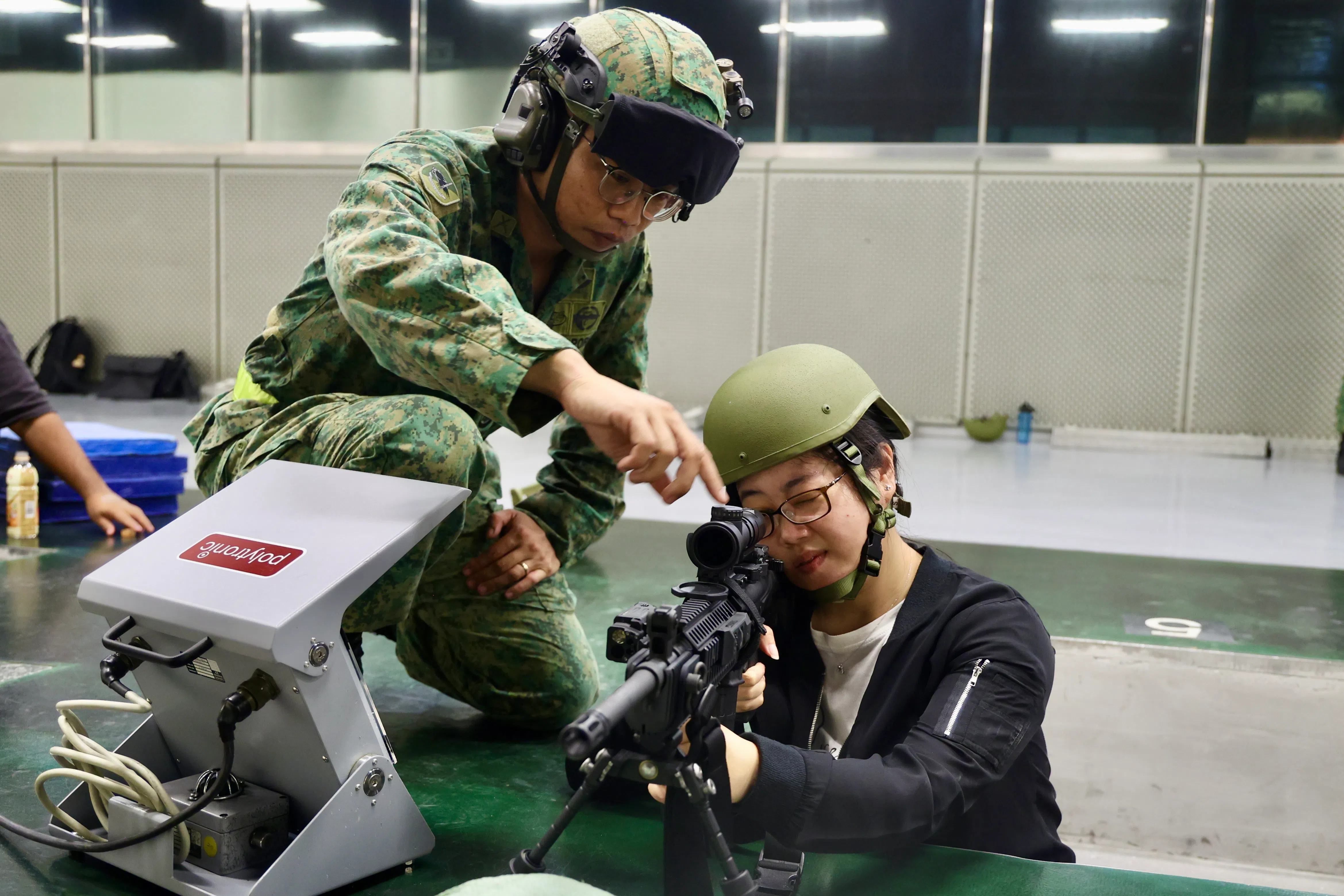 记者（右）星期三在巴西拉峇军营的室内实弹射击靶场中心，体验使用新引进的柯尔特自动步枪进行实弹射击。试射人员都有一名指导员从旁监督，以确认安全。（郑一鸣摄）