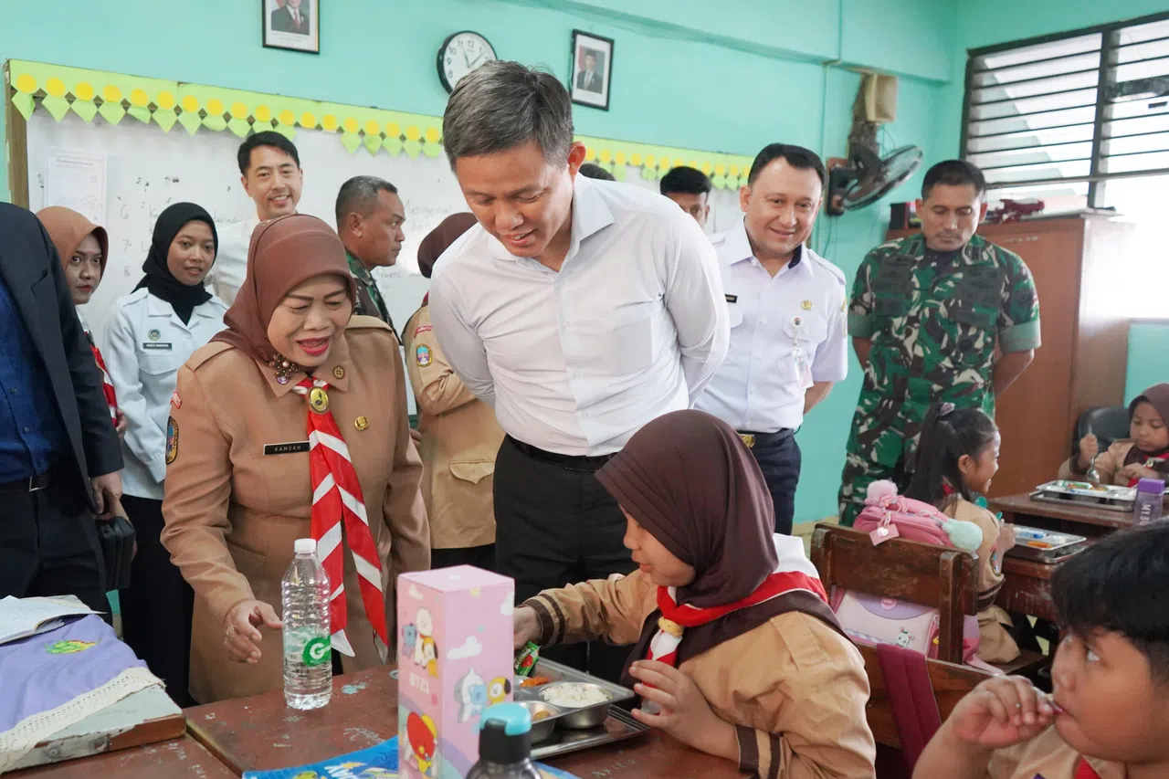 陈振声（左二）参观印尼国民军在“免费营养餐计划”下营运的厨房后，走访一所小学。这所小学的学生当天所吃的餐点，由国民军营运的厨房准备。（国防部提供）