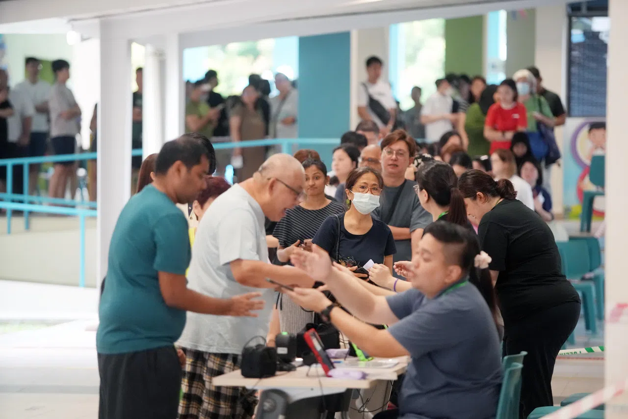 选民在进入投票站后出示身份证和投票卡，由工作人员扫描后就可前往投票区投票。尽管位于榜鹅河道小学的投票站早上出现人龙，但情况在一小时内基本见缓。（谢智扬摄）