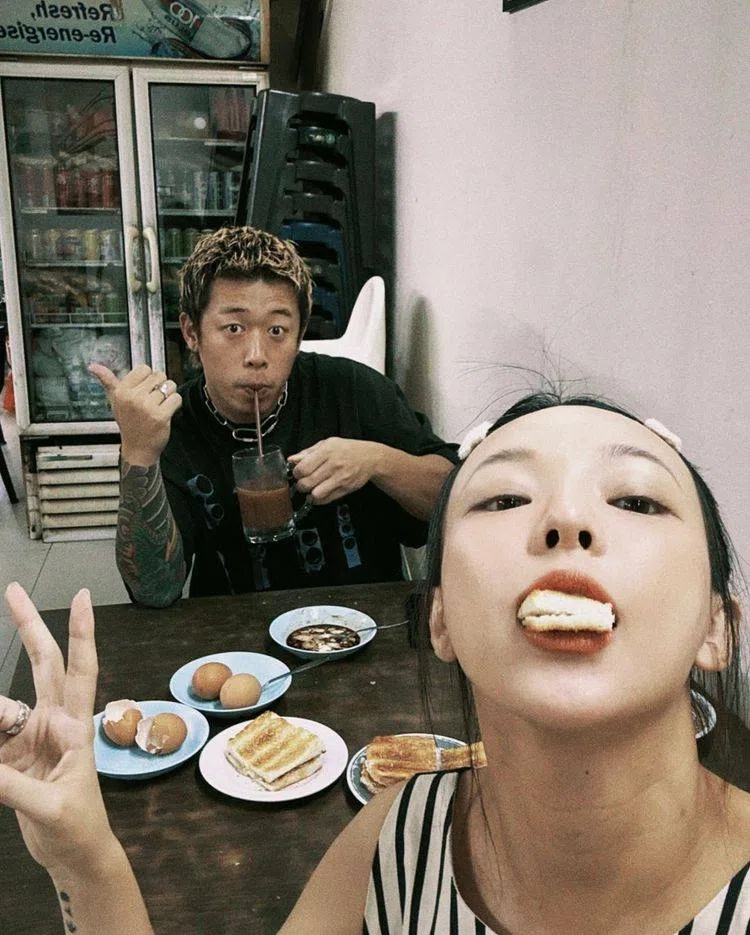 健志（左）与陈宁亚品尝新加坡特色小吃烤面包和半生熟鸡蛋。（取自陈宁亚Instagram）