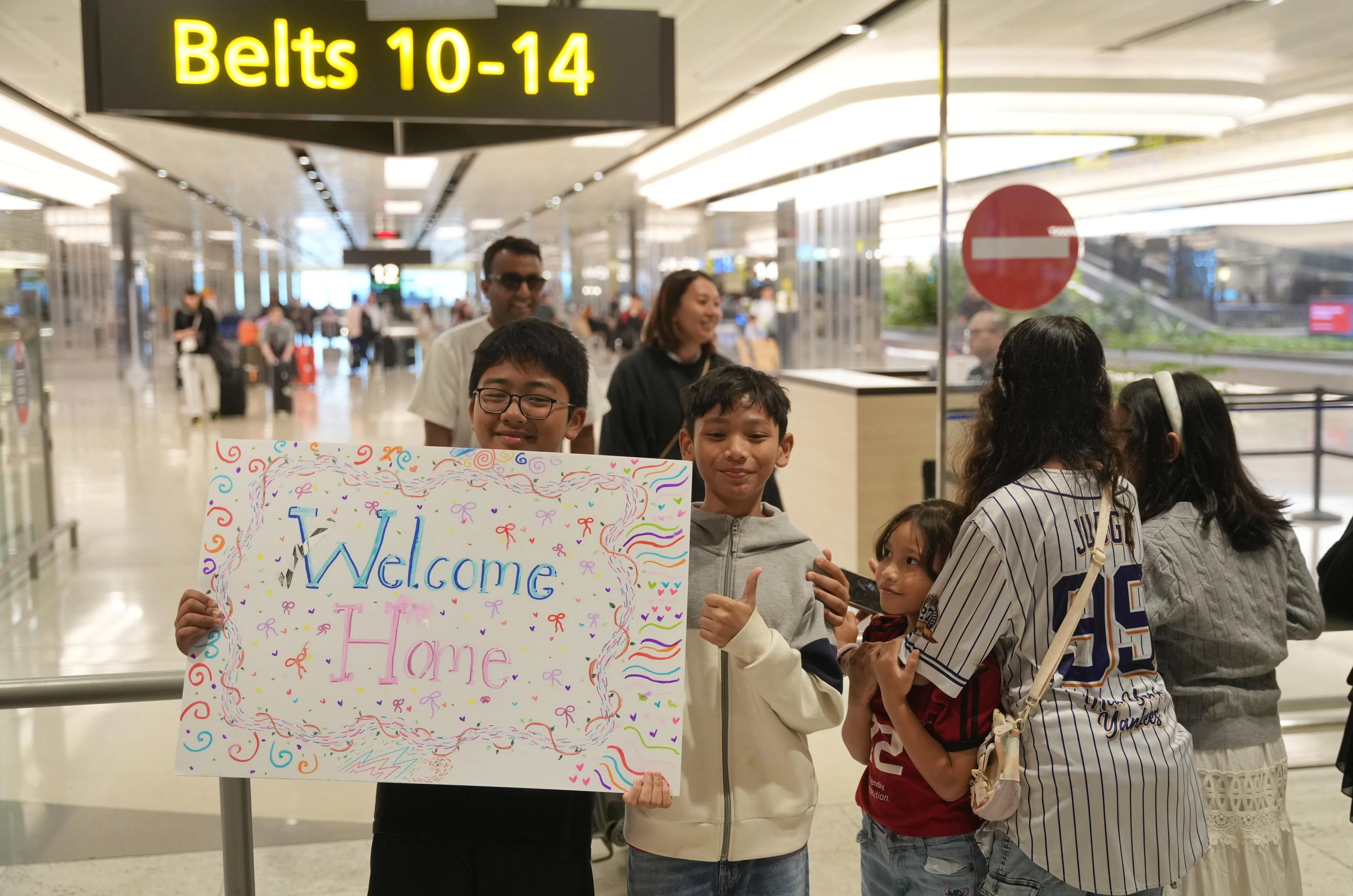 乘客的亲友在抵境大厅，拿着手写的欢迎贺卡等待他们安全归来。（谢智扬摄）