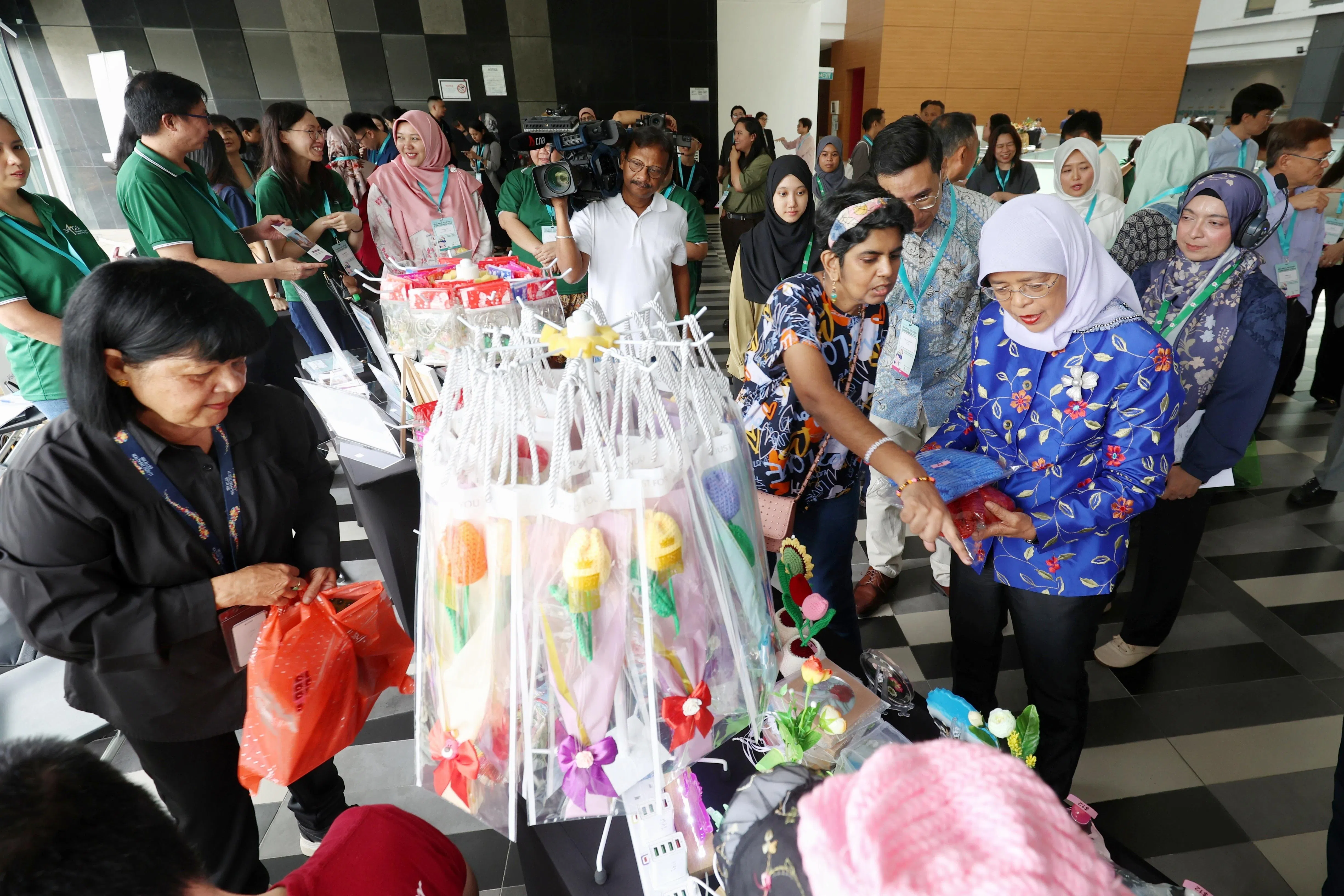 前总统哈莉玛（右一）出席社会服务机构Club HEAL举办的首届康复会议，并参观本地心理健康机构在会场设置的展位，了解它们提供的服务。（何家俊摄）