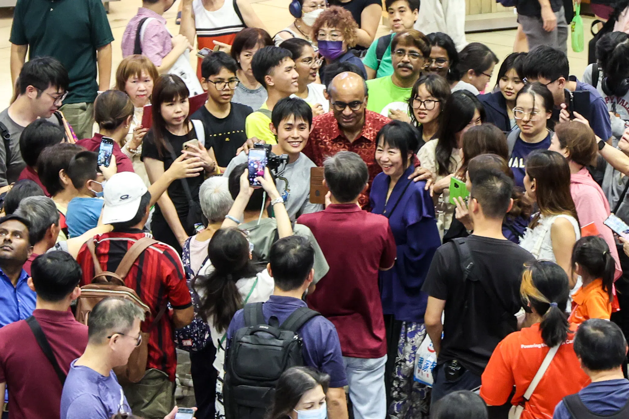 尚达曼（中间，穿红衣微笑者）在傍晚时分到老区大巴窑向民众问好。居民见到尚达曼，喜出望外，纷纷簇拥而上，与他握手合影。（关俊威摄）