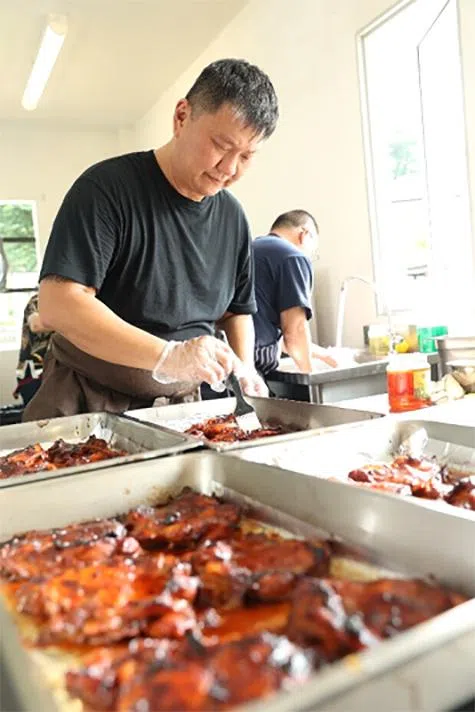 突破村庄主厨陈明裕（前）教导学员烹煮红烧鸡肉。他将与突破樟宜村法国餐馆主厨张德同共同负责培训任务，并参与中央厨房的设计和设备采购。（突破宣道之家提供）
