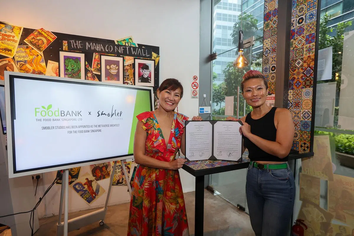 食物银行联合创始人黄玮婷（右）与陈仙凤签署合作协议，利用拍卖NFT来筹募资金，为受益人提供食物及日常所需。（档案照）