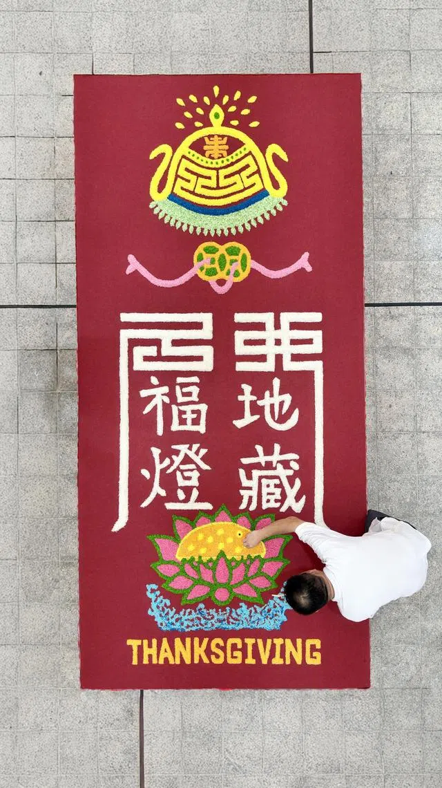 余义源在义安城广场举行的大型法会上，排出长24英尺、宽6英尺的米图。（龙国雄摄）