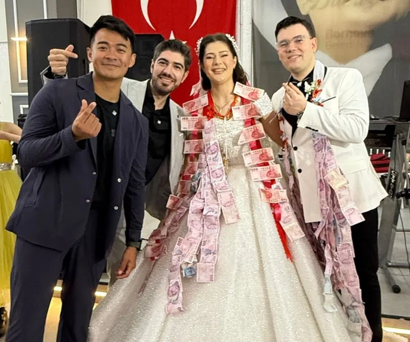 融融（左一）出席图佳妹妹的婚礼，还入乡随俗，为新娘献上串成一线的钞票当贺礼。（互联网）