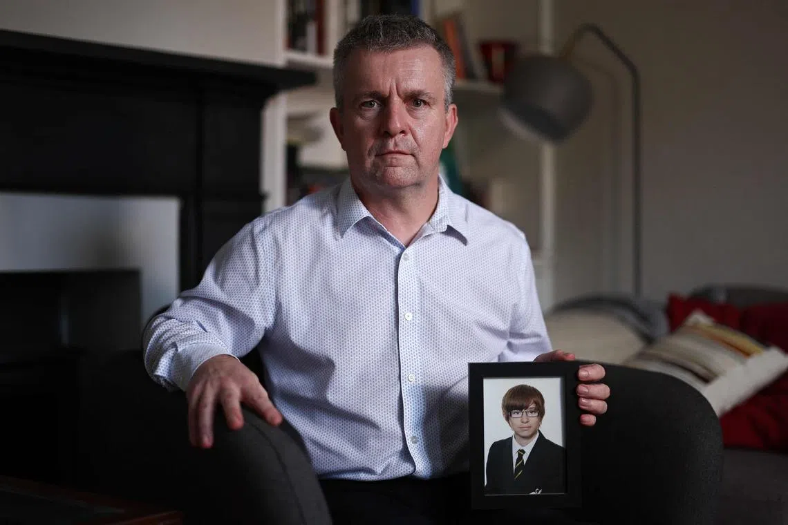 英国男子帕菲特2021年自杀身亡，当时年仅22岁。图为2023年，帕菲特的父亲拿着儿子的遗照。（法新社）