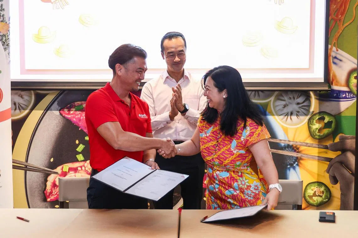 新加坡鲜农总会首席执行官张国健（左）和全国职工总会助理秘书长杨涴淩（右）签署谅解备忘录，双方要推动农业自动化和科技化等业务转型。永续发展与环境部兼人力部高级政务部长许宝琨医生（中）见证签署仪式。（白艳琳摄）