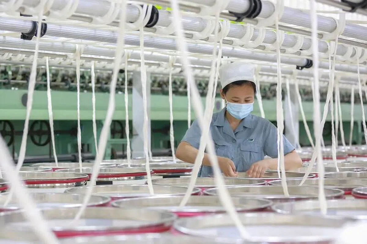 经济学人智库说，中国本身经济有较大的自给自足能力，对冠病病毒“零容忍”政策带来的压力相对比较小。图为安徽安庆一家纺织厂工人本月7日在工作中。（法新社）