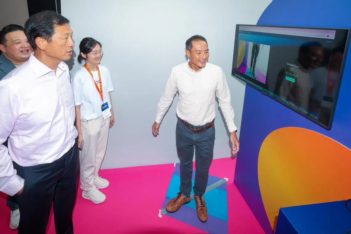 社会政策统筹部长兼卫生部长王乙康（左一）和数码发展及新闻部兼卫生部高级政务部长陈杰豪（右）星期一出席由新联科技举办的人工智能加速研讨会。图为陈杰豪在参观现场展览时，尝试ASPIRE的平衡测试。（吴先邦摄）