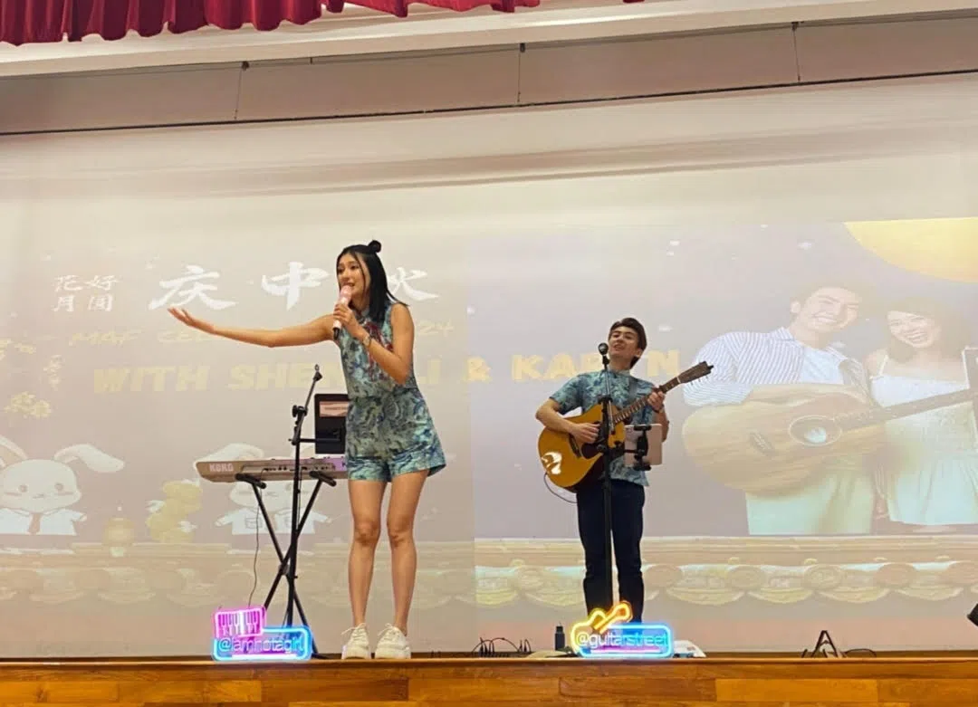 本地歌手黄诗敏（左）和苏晟立在中秋节庆祝活动中，为南侨中学师生献唱。（李佩嬣摄）