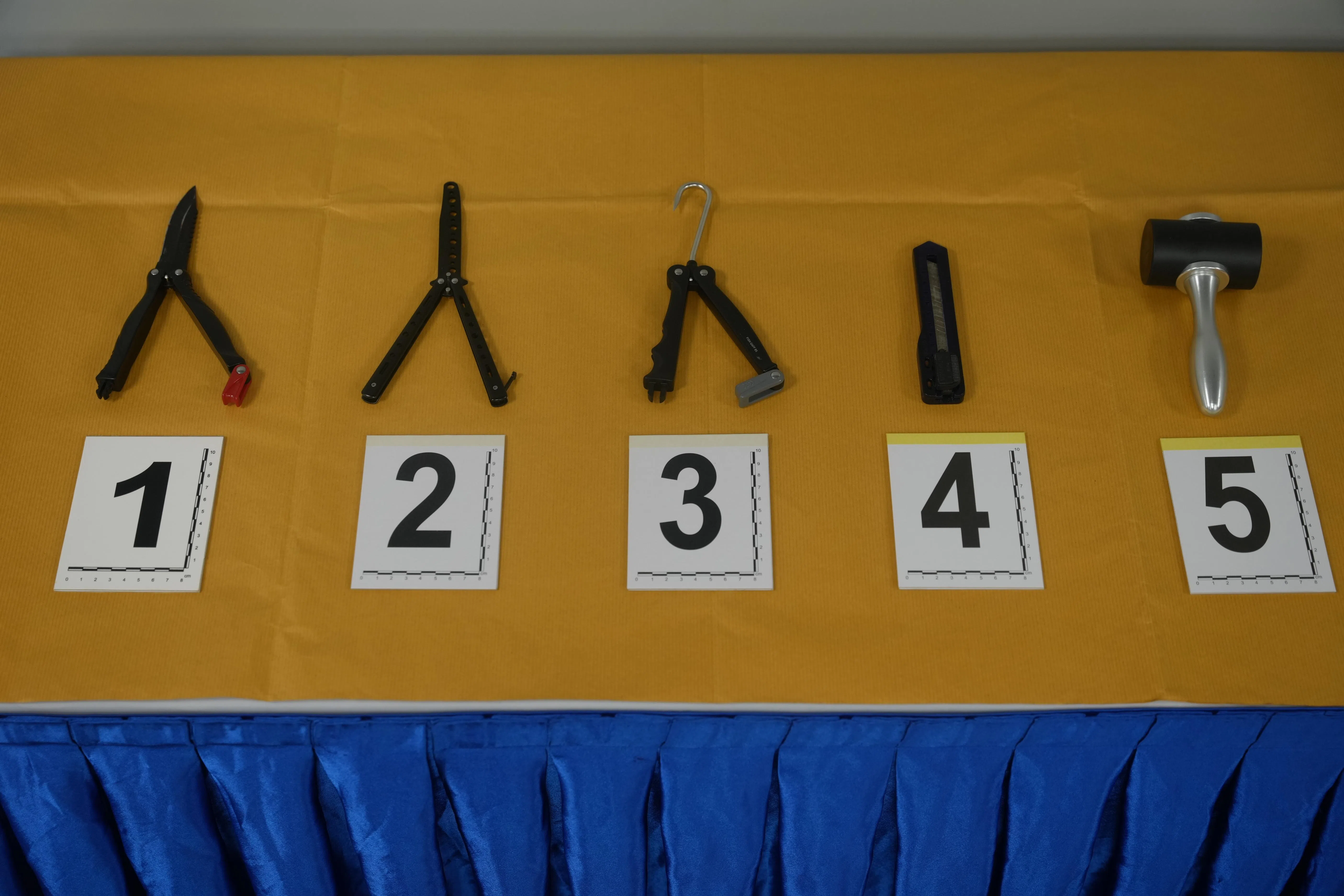 警方缴获男子干案时使用的折叠式小刀（左起），以及没有刀刃的蝴蝶刀、钩子、刀片和锤子。（谢智扬摄）