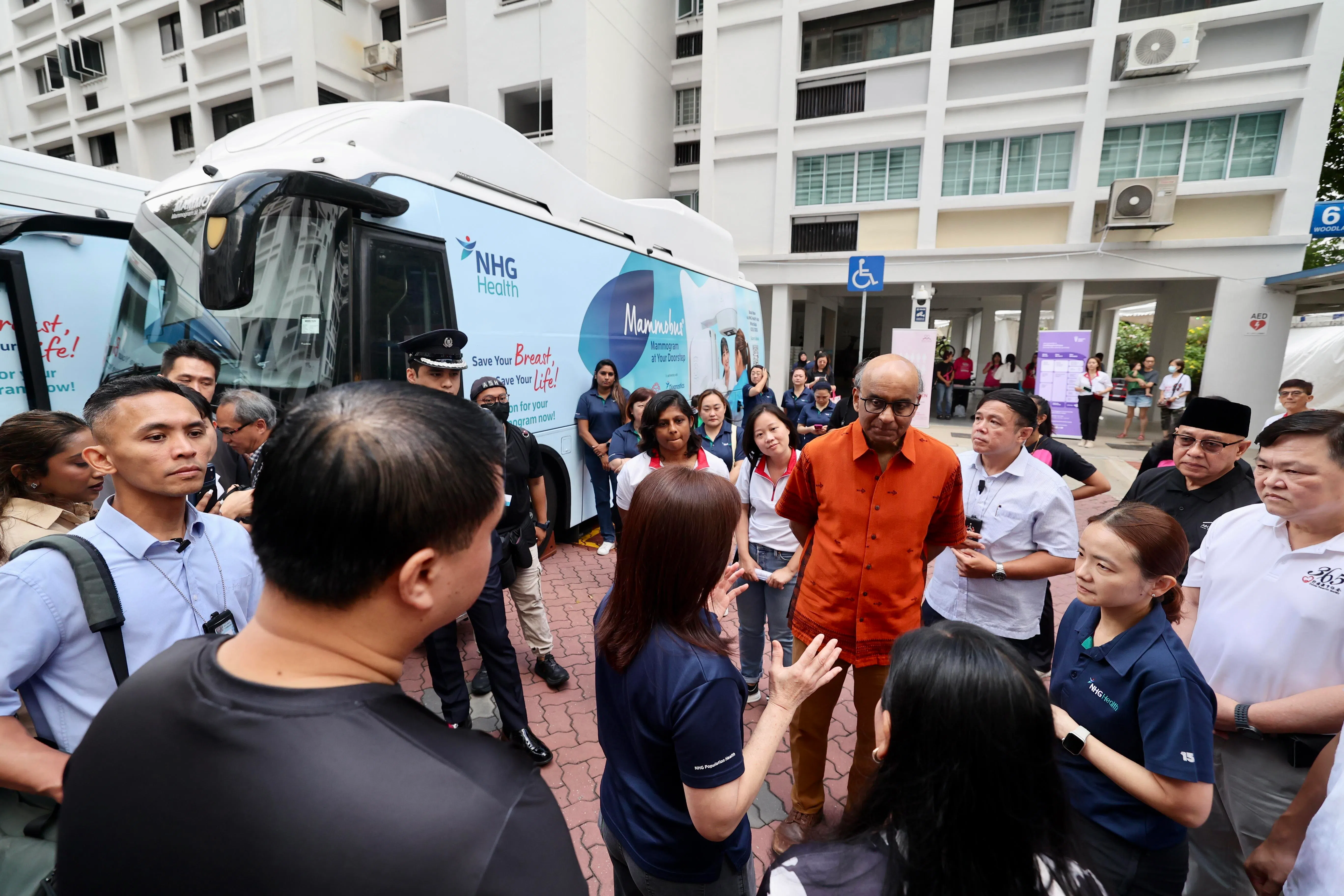 尚达曼总统（橘红色上衣者）聆听国立健保集团诊断部执行主任林素霞（背对镜头中）讲解，乳房X光检验流动巴士如何运作。（陈斌勤摄）