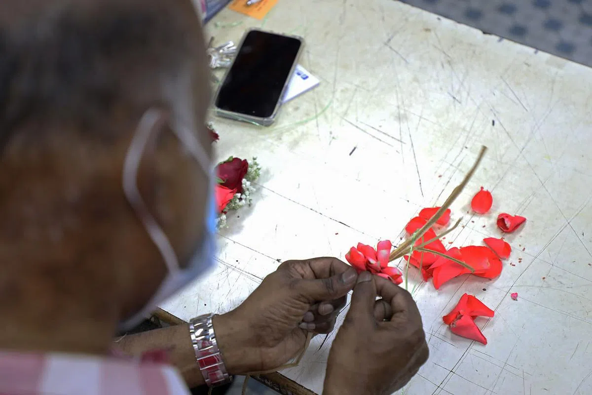 Selvam现场示范将玫瑰花瓣拆开后，一瓣一瓣卷起再绑在绳子上。