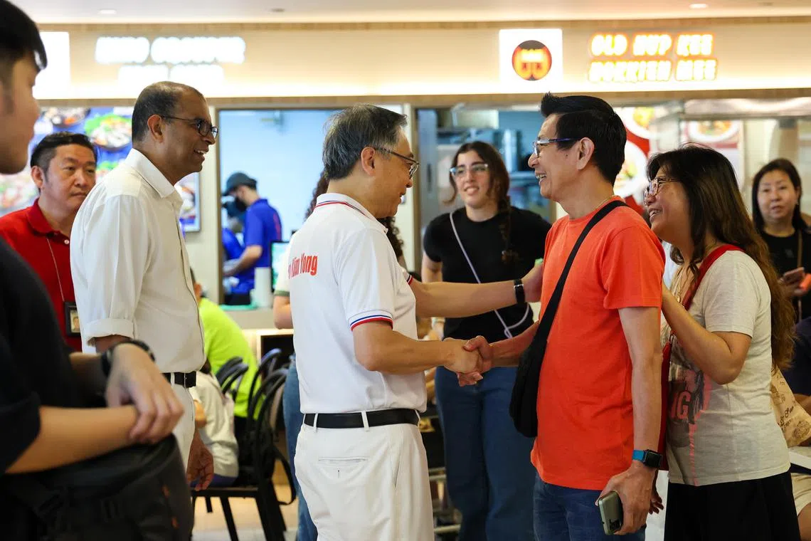 颜金勇（左四）和普杰立（左三）星期天在榜鹅谢票，途中不少居民主动上前打招呼。（林明顺摄）