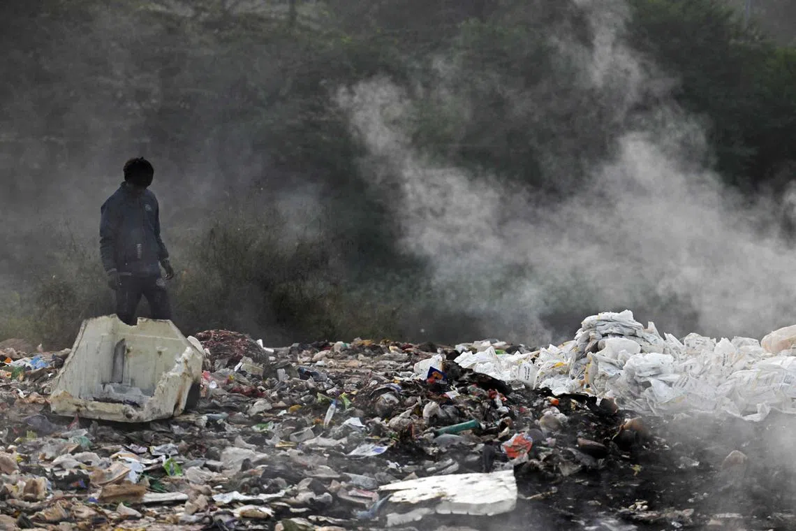 11月19日，一个男孩在新德里加济布尔（Ghazipur）垃圾填埋场焚烧着的垃圾堆中寻找可再用的垃圾。（法新社）